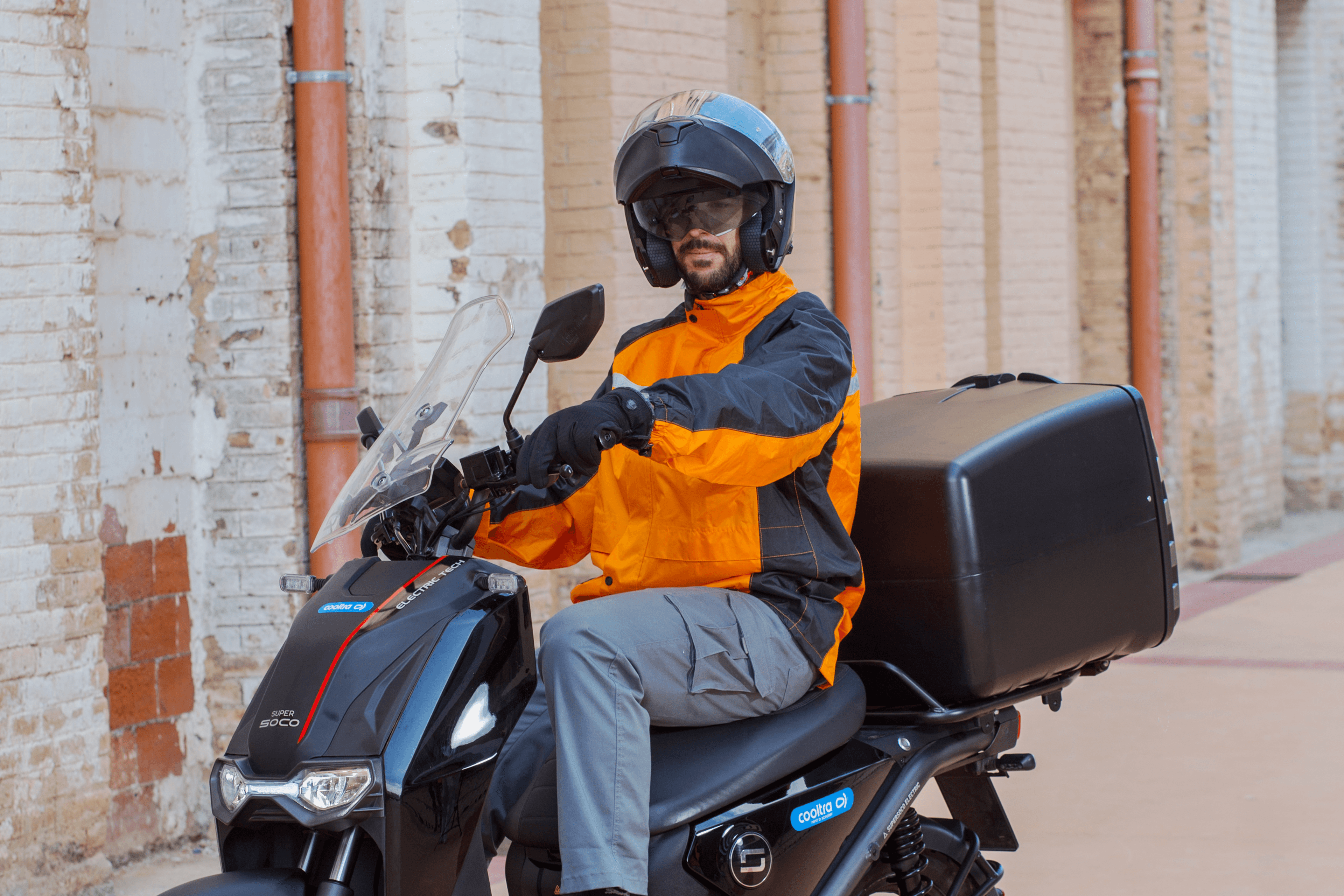 Personas con cascos posan con vehículos eléctricos en un entorno urbano.